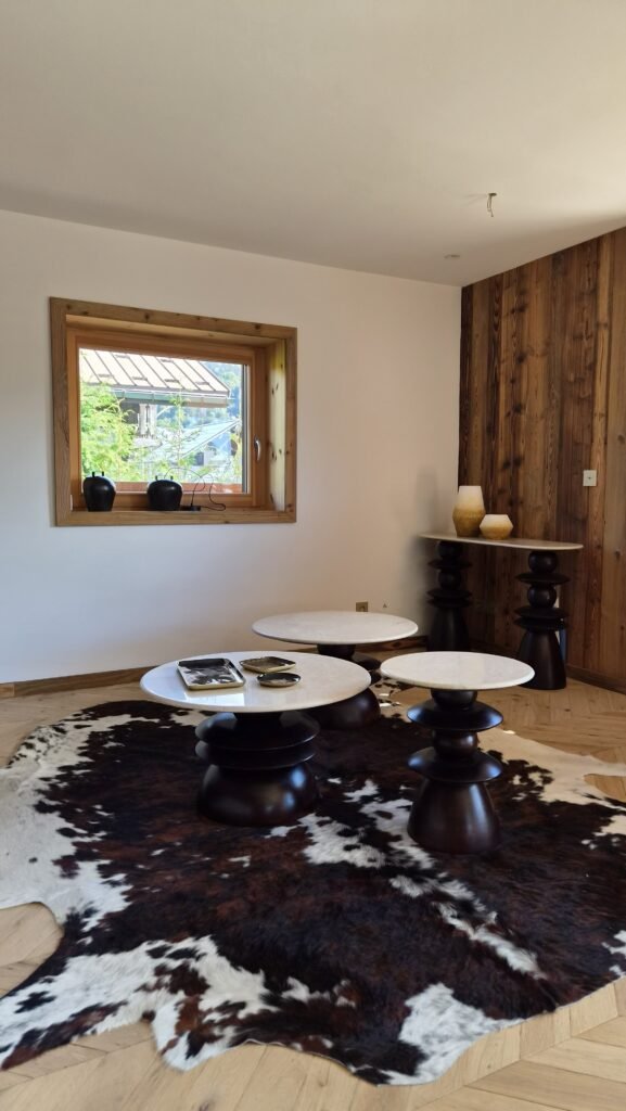 Salón de chalet, piel de vaca y mesas de madera torneadas en mármol